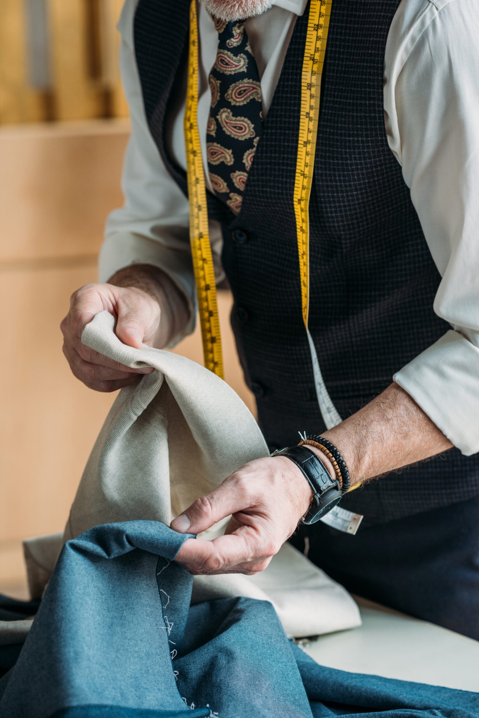 cropped image of tailor choosing cloth at sewing workshop